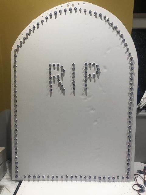 A white foam board tombstone outlined in pixels, with RIP spelled out in the middle